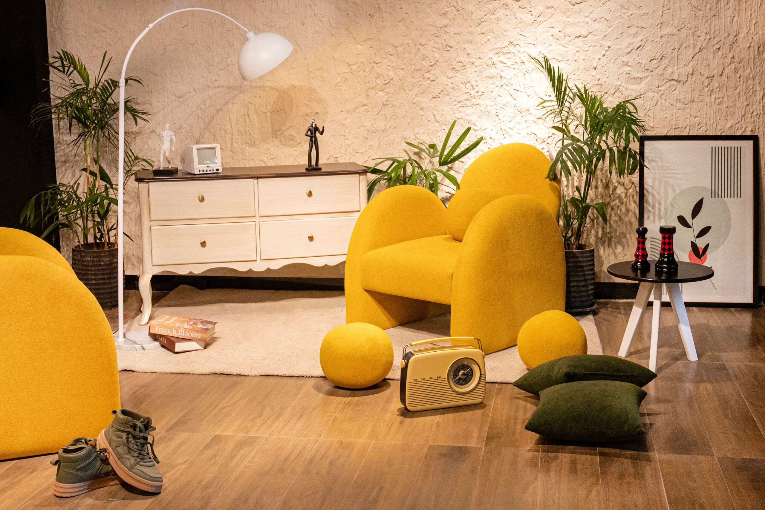 Warm living room setup with yellow chair, vintage radio, plants, and chic decor creating a cozy atmosphere.